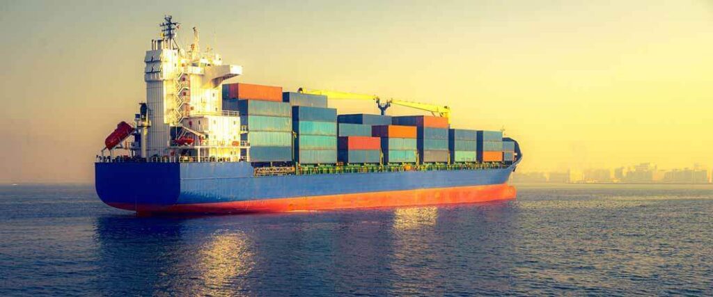 A cargo vessel at sea laden with stacks of cargo containers.