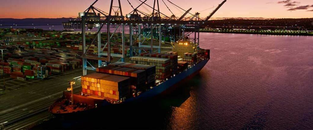 A cargo vessel docked at a port in the evening.