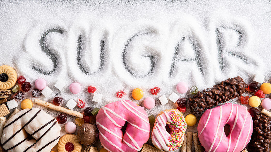 donuts and candies under pilled sugar with the letters S-U-G-A-R traced out