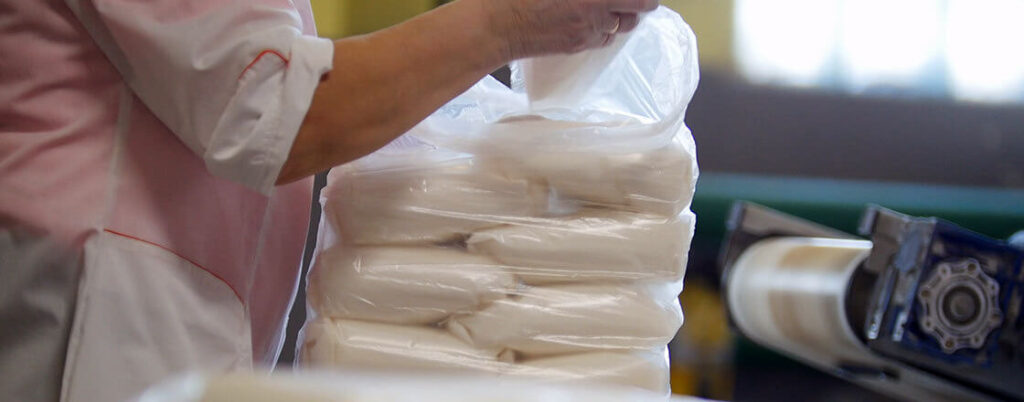 worker packing smaller bags of sugar into a large bulk sack