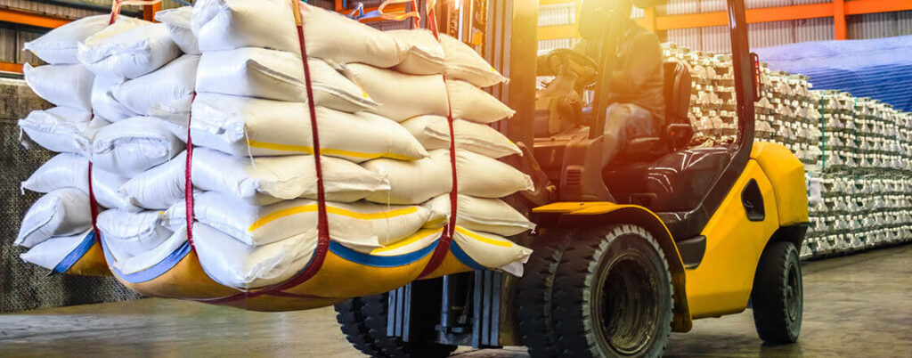 worker on a forklift moving large bags of sugar 