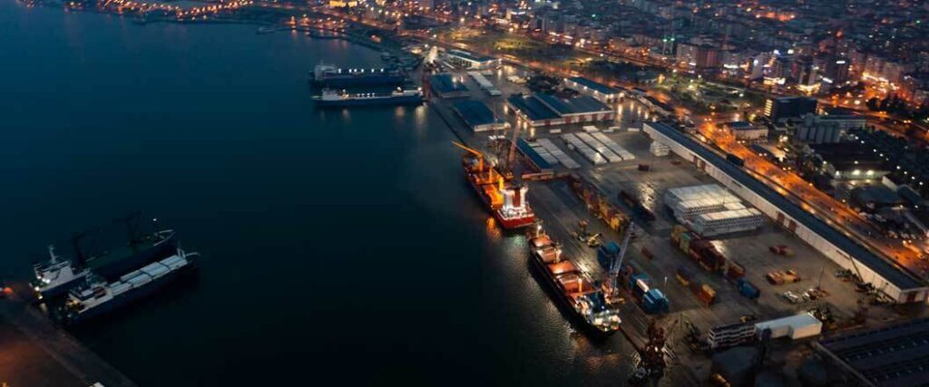 An overhead view of a port at night with multiple cargo vessels visible 