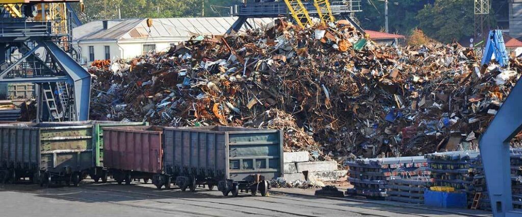 A pile of scrap metal next to railroad tracks.