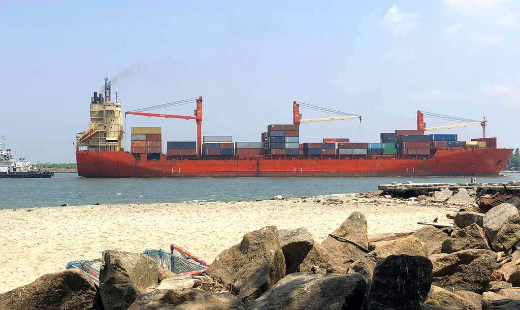 A cargo ship with containers being tugged out of port