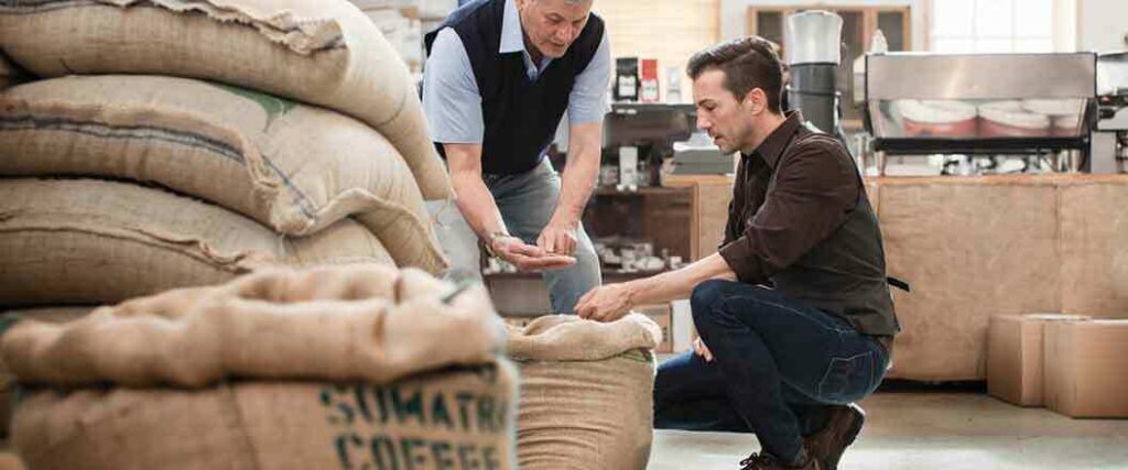 Two inspectors look through bags of coffee beans to determine their grade and quality. 