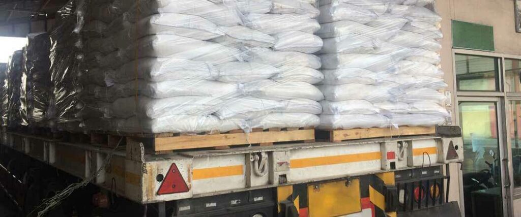 Sacks of dried chemical goods palletized and loaded onto a flatbed trailer for transport.